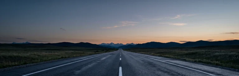 Empty Alberta highway at dusk with the Rocky Mountain foothills — dangerous driving defence in Alberta